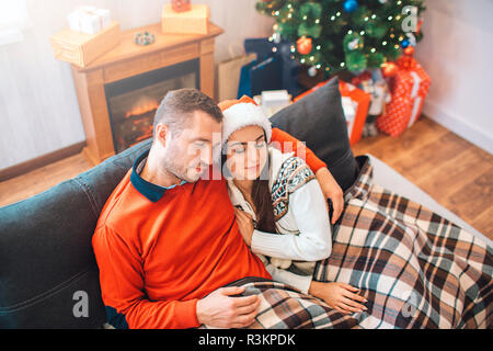 Beau couple sur un canapé. Ils se sont endormis. Il embrasse son. Elle se penche vers lui. Ils ont l'air jolie Banque D'Images