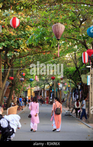 Deux femmes en vêtements traditionnels Ao Dai shopping dans les rues de Hoi An, Vietnam Banque D'Images