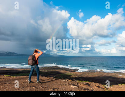 Las Palmas, Gran Canaria, Îles Canaries, Espagne. 23 novembre 2018. Météo : A female hiker donne vers un arc-en-ciel sur l'Océan Atlantique comme une pluie torrentielle, qui a balayé les îles Canaries au cours des 24 dernières heures, enfin efface Gran Canaria. Credit : ALAN DAWSON/Alamy Live News Banque D'Images