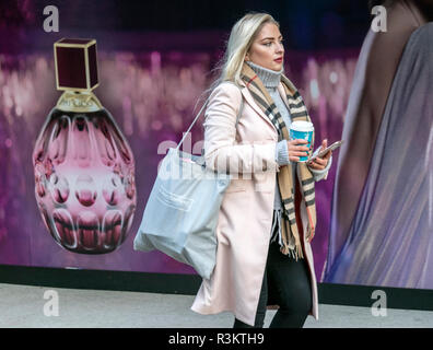 Manchester, Greater Manchester, UK. Femme passant Jimmy Choo Fièvre, nouvelle fragrance à Black Friday les ventes. 23 novembre 2018. Les gens affluent dans les magasins de la rue haute des affaires sur l'un des jours de shopping les plus importants de l'année. Les magasins sont emballés avec des acheteurs avisés à la recherche d'un Vendredi noir traiter juste à temps pour Noël. Credit : Cernan Elias/Alamy Live News Banque D'Images