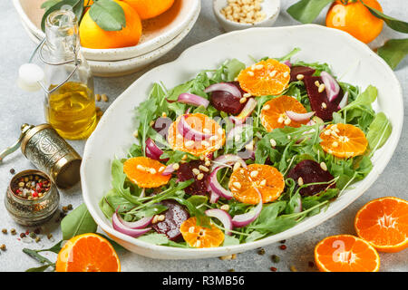Charcuterie salade de betteraves cuites colorées, la roquette, les tangerines et les oignons rouges, les épices et les noix de pin blanc dans un plat. L'huile d'olive et d'ingrédients sur Banque D'Images
