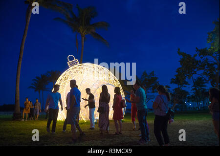 MIAMI - CIRCA DÉCEMBRE 2017 : Les visiteurs se réunissent pour prendre des photos en face d'un gigantesque sapin noël ornement situé dans les palmiers de Lummus Park. Banque D'Images