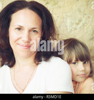 Smiling young adult Caucasian mother avec sa petite fille, close-up portrait. Vintage photo carré stylisé avec effet de filtre de correction tonale, j Banque D'Images