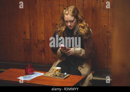 Woman using mobile phone in cafe Banque D'Images