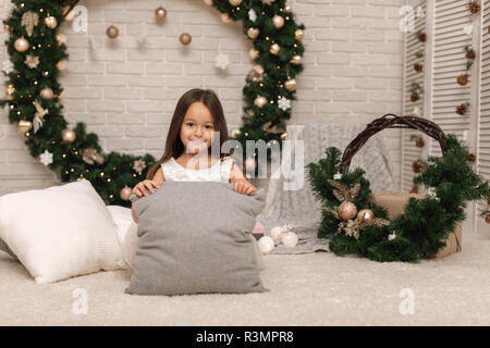 Happy girl sur l'arrière-plan de la couronne de Noël à la maison. Banque D'Images