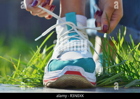 Jeune fille attacher ses lacets de chaussures de sport du comité permanent sur l'herbe verte close-up view photo horizontale, journée ensoleillée Banque D'Images