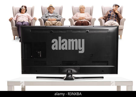 Deux femmes âgées et deux hommes âgés assis dans des fauteuils et regarder la télévision isolé sur fond blanc Banque D'Images