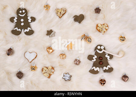 Gingerbread men et biscuit en forme d'étoiles et de coeurs lying together avec boules de Noël en or sur un cuir blanc. Photographié à partir de Banque D'Images