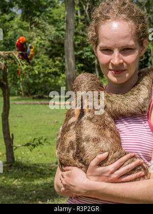 Portrait d'une jeune fille avec un paresseux accroché sur son épaule. Un paresseux je la lenteur des mammifères de l'Amérique tropicale qui pend la tête en bas aux branches Banque D'Images