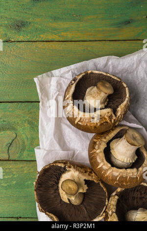 Faire revenir les champignons crus frais et les feuilles de persil branche sur fond peint en vert en bois rustique. Banque D'Images