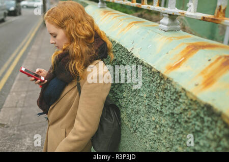 Femme à l'aide de téléphone mobile dans une ruelle Banque D'Images