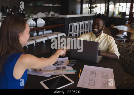Business colleagues shaking hands in cafeteria Banque D'Images