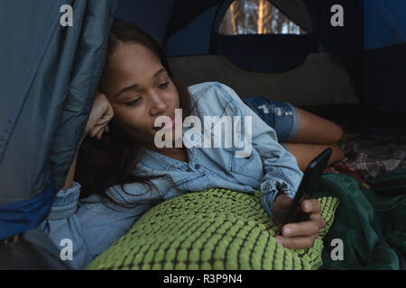 Woman using mobile phone in tent Banque D'Images