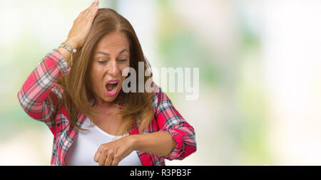 Belle femme d'âge moyen portant sur fond isolé à la fois à la montre inquiet, peur de se faire tard Banque D'Images