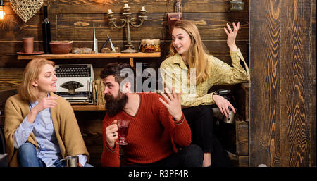 Les amis de s'amuser, parler et boire des boissons chaudes dans un intérieur en bois. Homme et femmes sur visages heureux de discuter et de boire du vin. Communicatio Banque D'Images