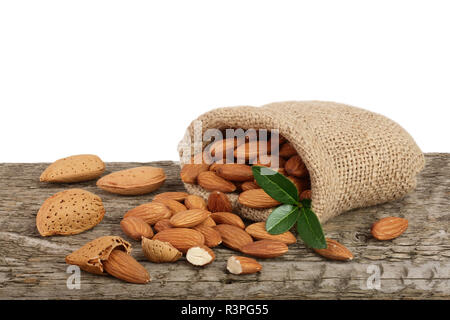 Amandes avec feuille dans sac du sac sur une table en bois avec un fond blanc Banque D'Images