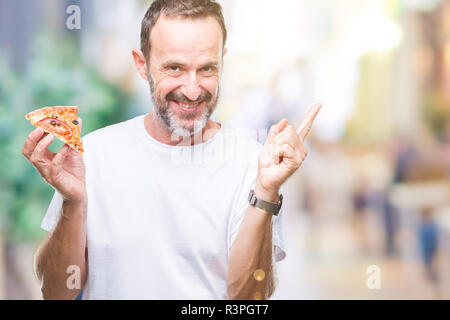 L'âge moyen des cadres supérieurs des man eating pizza slice sur fond isolé très heureux pointant avec la main et le doigt sur le côté Banque D'Images