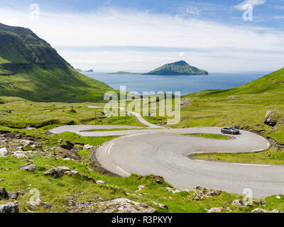 Route de montagne à l'Nordradalur à la côte ouest. L'île de Koltur en arrière-plan. Le Danemark, Îles Féroé Banque D'Images