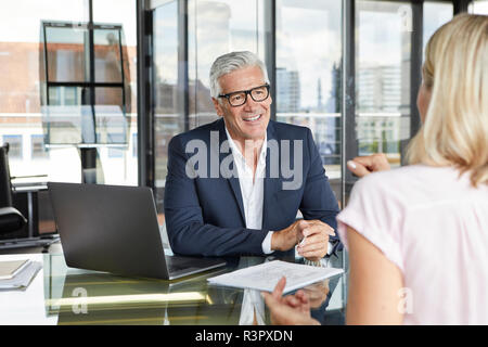 Businessman snd woman sitting in office, discussing project Banque D'Images