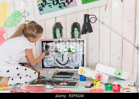 Girl painting des oreilles de lapin sur PC in office Banque D'Images