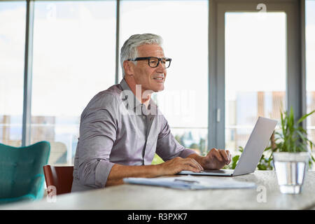 Mature man using laptop sur la table à la maison Banque D'Images