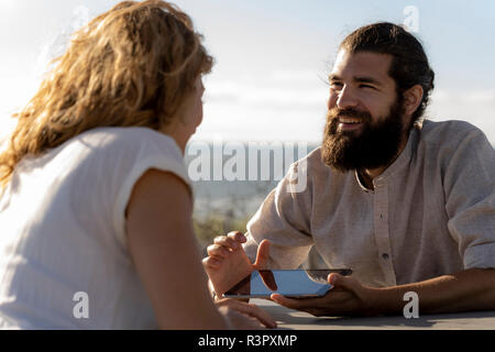 Jeune couple assis, d'un at une table à la plage Banque D'Images