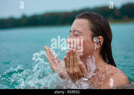 Jeune femme dans le lac de baignade avec de l'eau éclaboussant Banque D'Images