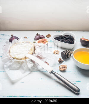 Le camembert sur du papier d'emballage blanc, avec de la confiture, noix et miel, figues fraîches, sur un fond de bois rustique place pour le texte Banque D'Images