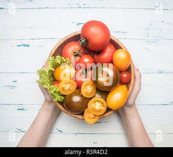 Différentes couleurs de la ferme biologique de légumes de différentes variétés de tomates, légumes frais dans un bol en bois de femmes sur un fond rustique, Banque D'Images