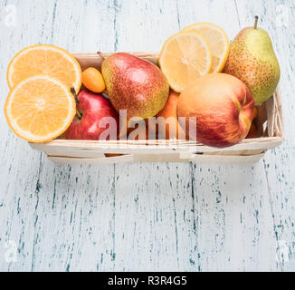 Ensemble de fruits, poires, oranges, kumquats, pommes, dans un panier blanc sur un fond blanc en bois rustique, place pour le texte Banque D'Images