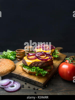 Délicieux hamburgers maison avec une viande juteuse, hacher l'oignon rouge, fromage, salade et tomates, sur un millésime à découper, Close up, de l'espace pour le texte Banque D'Images