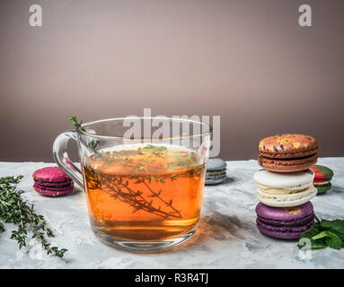 Tisane chaude en bonne santé aux fruits rouges, de thym et de menthe, appétissant, macarons multicolores, empilés sur un fond rustique blanc, l'espace pour le texte Banque D'Images