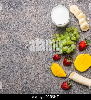 De l'air et de la santé ou de régime de detox food concept. Ingrédients pour les smoothies à base de bananes, mangues, fraises et raisins, frontière, place pour le texte Banque D'Images