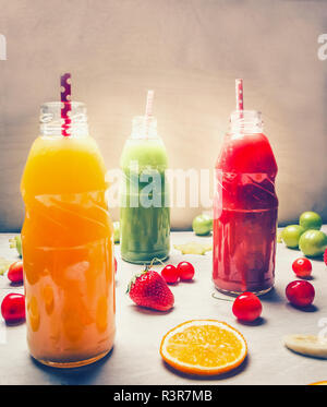 Variété de smoothies colorés ou des bouteilles de jus de fruits smoothies avec divers ingrédients sur fond de bois blanc, vue du dessus. De l'air et en bonne santé Banque D'Images