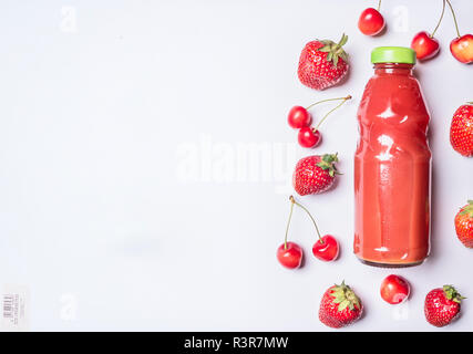 Red Fruits smoothies avec divers ingrédients dans une bouteille en verre avec fraises et cerises sur fond de bois blanc pour le texte place frontière Banque D'Images