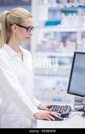 Female pharmacist working on computer en pharmacie. Banque D'Images