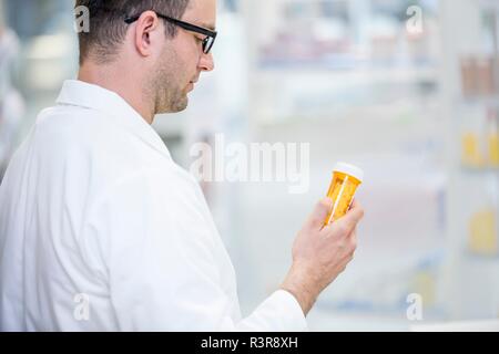 Pharmacien reading label on bouteille de pilules en pharmacie. Banque D'Images