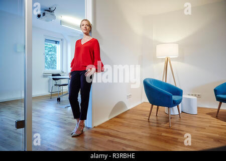 Portrait of young woman leaning against porte in office Banque D'Images