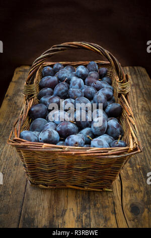 Panier en osier de prunes bio, table en bois Banque D'Images