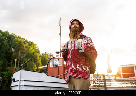 La Finlande, Kajaani, joyeux jeune homme. Le port de veste, houded standing on Jetty, carrrying sac à dos Banque D'Images