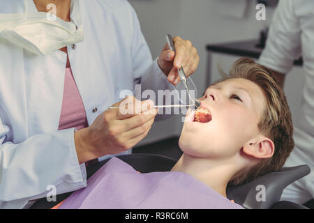 Examiner les dents dentiste garçon avec des instruments dentaires Banque D'Images