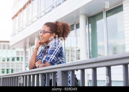 Pensive young woman leaning on railing à distance à Banque D'Images