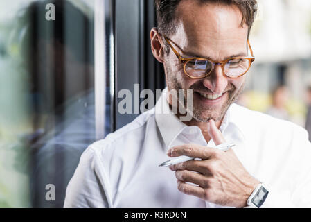 Portrait of laughing businessman wearing glasses et smartwatch Banque D'Images