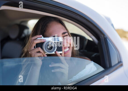 Femme assise en voiture, prendre des photos avec un appareil photo Banque D'Images