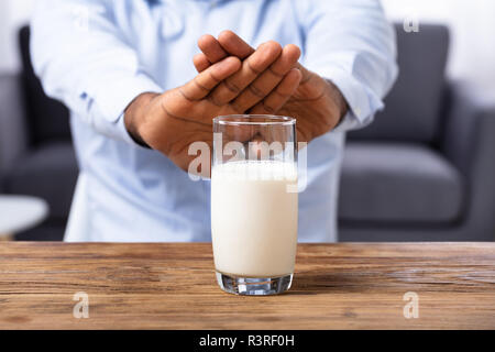 Close-up de la main d'un homme refusant Verre de lait sur un bureau en bois Banque D'Images