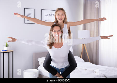 Portrait Of A Smiling Mother and Daughter avec bras tendus à la maison Banque D'Images