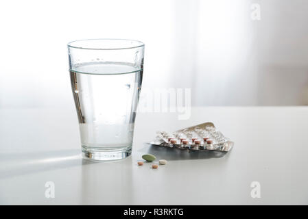 Comprimés et un verre d'eau sur la table de chevet blanc, copie, espace de discussion sélectionné, la profondeur de champ étroite Banque D'Images