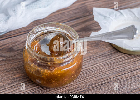 Pot en verre rempli de confiture de figues sur fond de bois. Banque D'Images