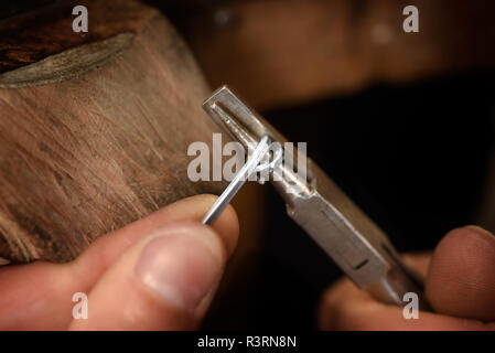 Goldsmith mains enveloppez le fil argenté avec une pince dans une spirale de petits anneaux de la chaîne, macro shot with copy space, choisis focus, réduire la profondeur de champ Banque D'Images