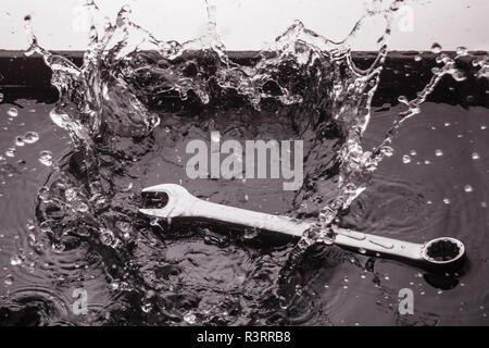 Clés plates de tailles différentes sur un fond sombre dans un jet d'eau. Banque D'Images